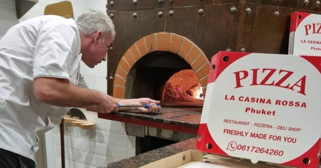 A worker at La Casina Rossa working at the pizza oven